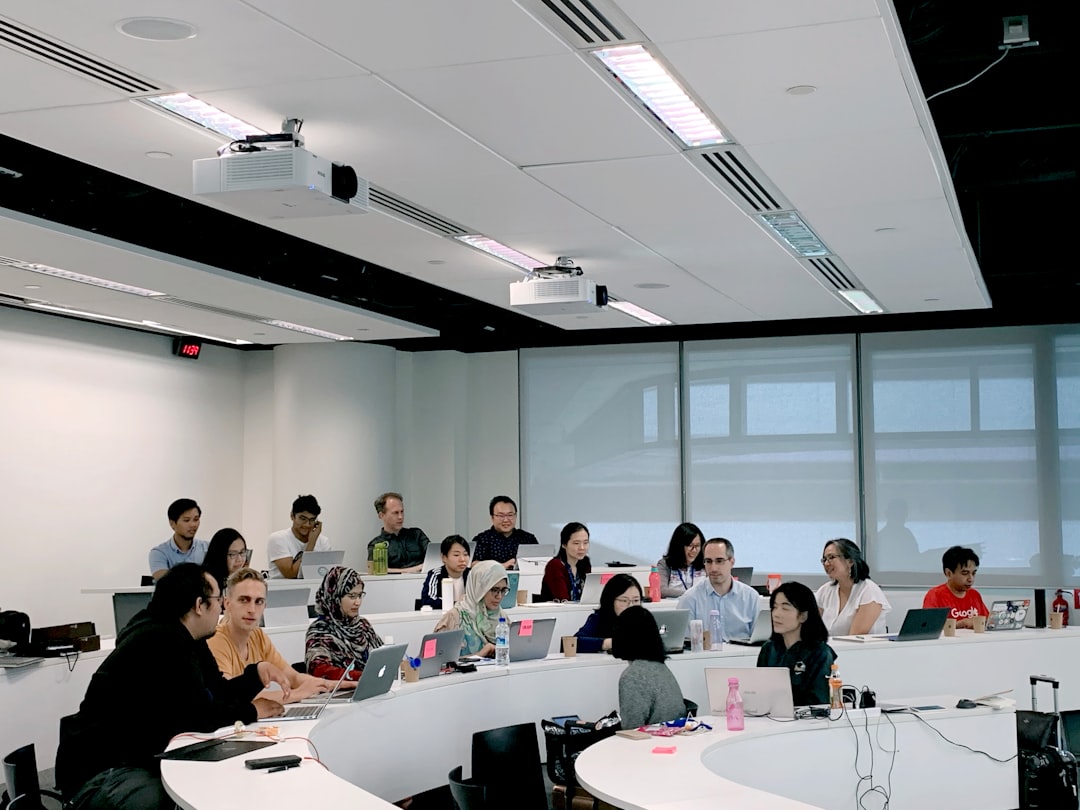 People seated at laptops in a classroom training session facing an instructor