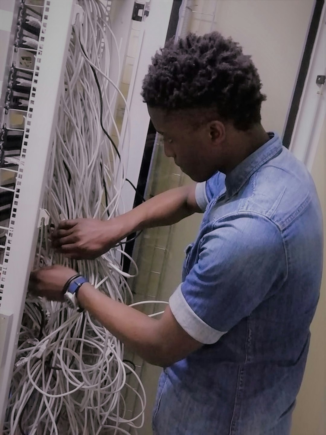 Engineer patching cables at the back of a server rack
