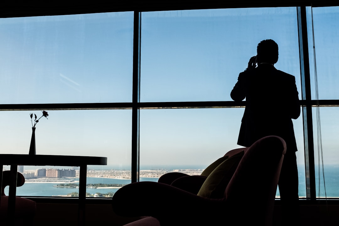 Man on the phone at a window overlooking the Dubai coastline