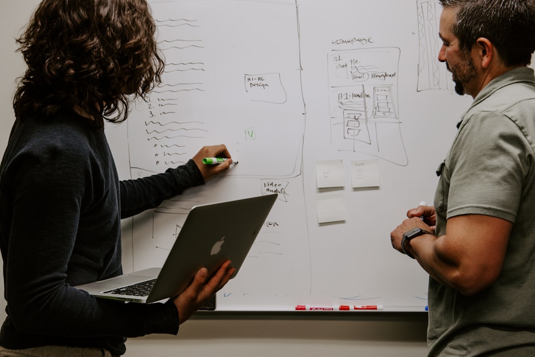 Two engineers working through a system diagram on a whiteboard